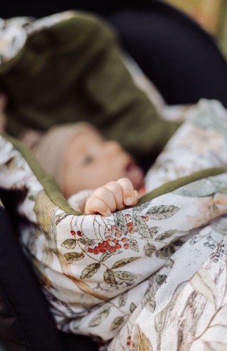 Kocyk do fotelika 100% bawełna z ciepłym wypełnieniem – Taste of Summer. Zbliżenie na dziecko w foteliku gdy kocyk jest rozpięty.