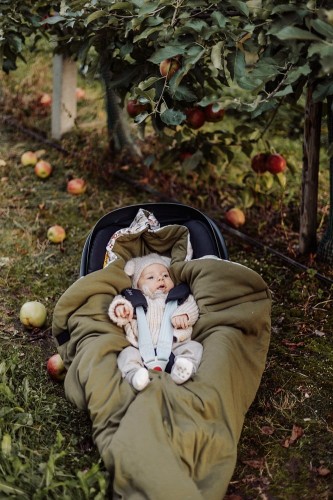 Kocyk do fotelika 100% bawełna z ciepłym wypełnieniem – Ornithology. Zbliżenie na dziecko śpiące w foteliku gdy kocyk jest zapięty.